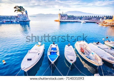Nafpaktos bay, Greek small town, famous and popular travel destination with old castle at the bank of sea. Row of motor boats anchored in marine. Sunrise beautiful scenery.