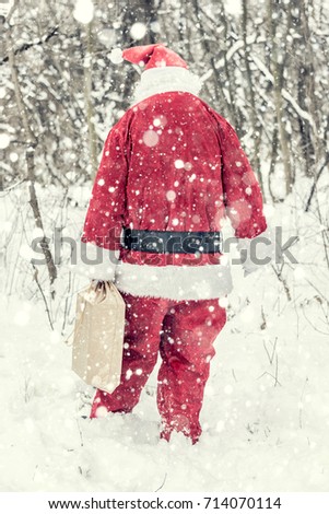 Santa Claus walking in the woods and holding presents 