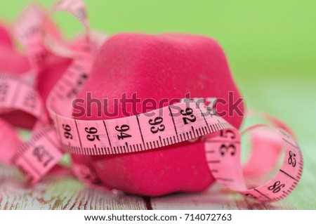Soft focus of measuring tape with dumbbell on wooden table. Healthy and exercise concept
