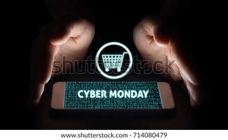 Man hands holding smart phone with cyber monday text and cart on virtual screens on smartphone.
