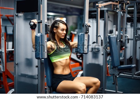 Young and sporty woman using pectoral fly machine in the gym Royalty-Free Stock Photo #714083137