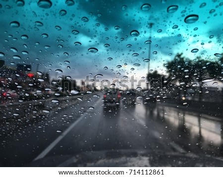 Blurry background, Raindrops on the windshield, street lights at evening on a rainy day, car windshield view.