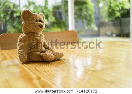 Cute teddy bear sits alone on wooden table