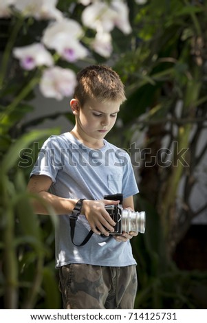 Boy shooting with a vintage medium format camera in a garden