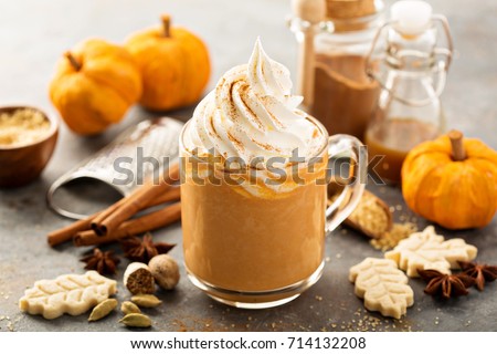 Pumpkin spice latte in a glass mug with cinnamon, nutmeg and cookies