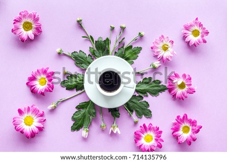 Floral pattern with cup of coffee on purple background top view