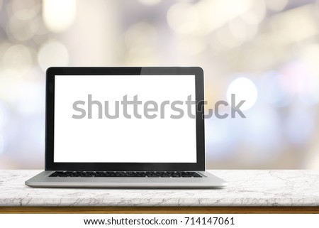 Mock up Blank screen of Laptop on white marble table in Co-working or cafe.