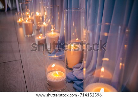 Festive greeting card and candles. Wedding decorations. Candles in glass vases, blue light. wedding decorations with flowers. picture with soft focus