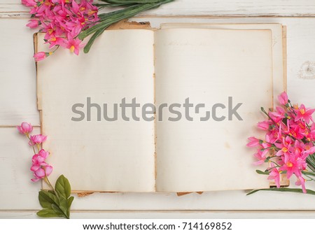 Opened and Blank Vintage Journal Paper or Stationary Book with Pink Feminine Flowers on Shabby Chic White Board Table Background.  A horizontal from Above View of the Pretty Flat Lay Arrangement. 