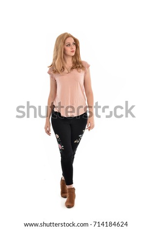 
full length portrait of girl wearing simple pink shirt and pants, standing pose on white studio background.