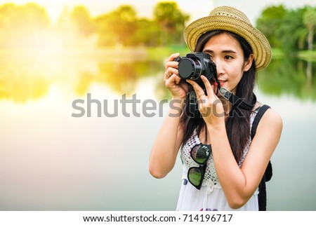 Asian woman photographer taking photo beside the marsh on vacation.
