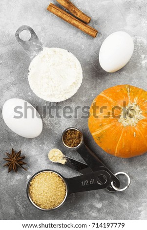 Ingredients for pumpkin pie - flour, pumpkins, eggs, cane sugar, various spices (nutmeg, ginger, cinnamon, anise) on a gray background. Top view. Food background