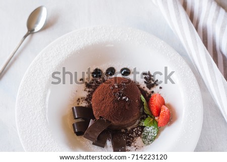 Delicious chocolate dessert on white plate with decoration from strawberry and mint. Fondant serving in restaurant for real gourmet