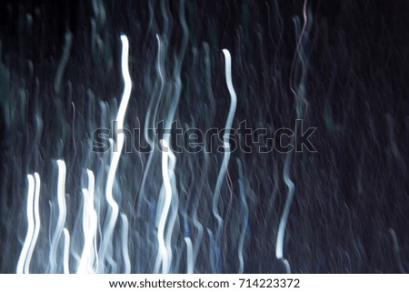 Abstract background of white waves in motion on black. Bokeh of defocused vertical curves, blurred neon leds of serpentine, festive backdrop of holidays, fireworks and celebrations
