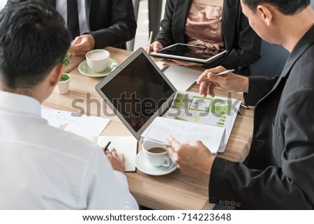 Business man looking on the marketing analysis statistics chart paper for sale forecast at the end of the year in a business meeting, teamwork is the ability to work together toward a common vision.