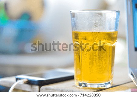 Glass beer on wood table and laptop in stock photographer concept.