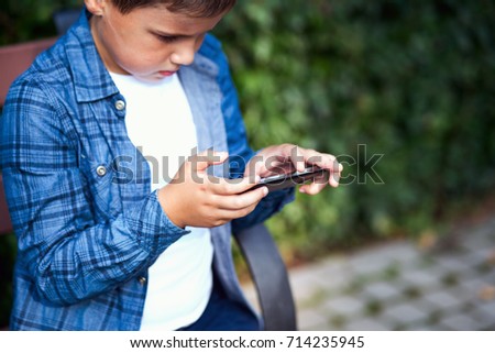 boy playing phone outdoors