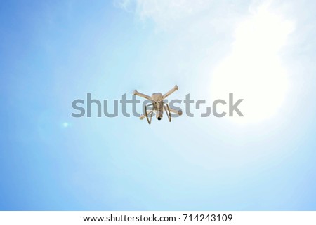 Sun in blue sky.  Remote controlled drone equipped with high resolution video camera flying in air and sunset blue sky.  