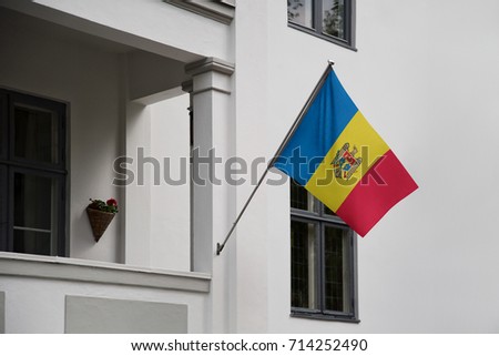 Moldova flag. Moldavian flag displaying on a pole in front of the house. National flag of Moldova waving on a home hanging from a pole on a front door of a building.