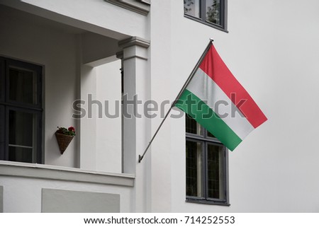 Hungary flag. Hungarian flag displaying on a pole in front of the house. National flag of Hungary waving on a home hanging from a pole on a front door of a building.