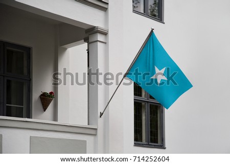 Somalia flag. Somalian flag displaying on a pole in front of the house. National flag of Somalia waving on a home hanging from a pole on a front door of a building.
