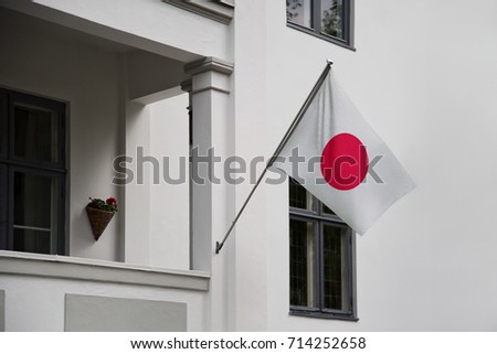 Japan flag. Japanese flag displaying on a pole in front of the house. National flag of Japan waving on a home hanging from a pole on a front door of a building.