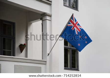 New Zealand flag displaying on a pole in front of the house. National flag of New Zealand waving on a home hanging from a pole on a front door of a building.