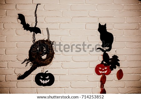 Halloween holiday celebration symbols. Black and red pumpkins, cat, bat, tree leaves and nest silhouette paper cutouts on beige brick wall. Mystery and superstition concept.