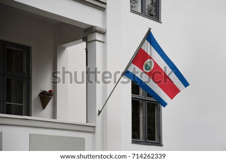 Costa Rica flag. Costa Rican flag displaying on a pole in front of the house. National flag of Costa Rica waving on a home hanging from a pole on a front door of a building.