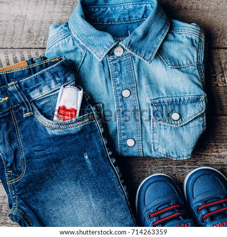 Top view, Flat Lay of Baby clothes blue jeans, sneakers, shirt and white baby kids car for game on wooden background. Top view