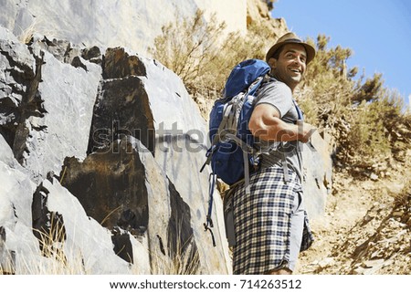 Smiling hiker guy in hat, looking over shoulder