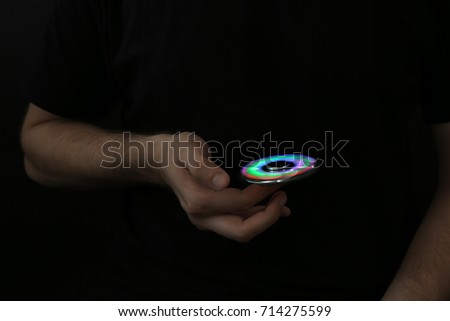 Man rolling modern luminous spinner on dark background