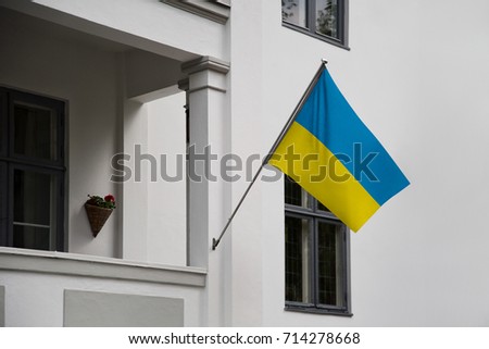 Ukraine flag. Ukrainian flag displaying on a pole in front of the house. National flag of Ukraine waving on a home hanging from a pole on a front door of a building.