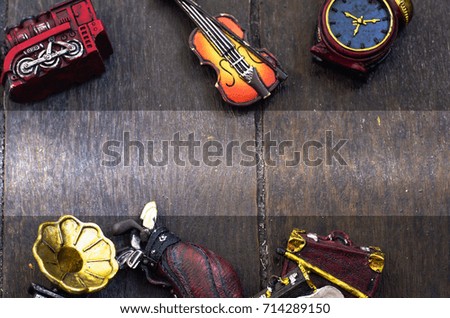 hobby and leisure cropped object concept image, miniature violin, clocks,travel bag and train on wooden floor. text space on center