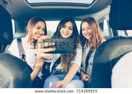 Happy group of girls friends making a selfie sitting on the back of a car on a journey