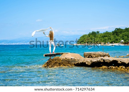 A beautiful young woman enjoying the wind and climate in the summer at the ocean.
