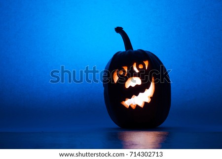 Halloween pumpkin, silhouette of funny face on blue background. Vertical