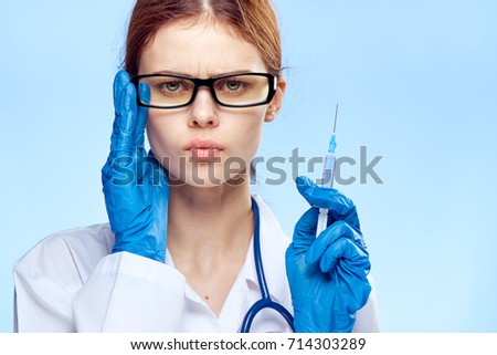 doctor serious with glasses holds a syringe on a blue background portrait                               