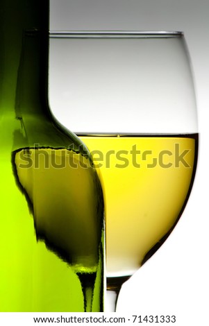 White wine in a wine glass behind a green wine bottle