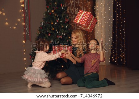 Mother and children exchanging and opening Christmas presents.