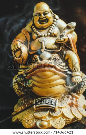 Burning incense sticks with laughing golden Buddha on the toad
