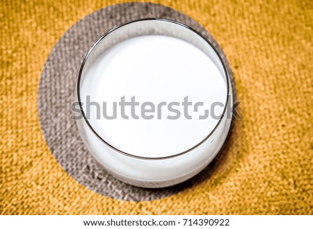 Top view of milk on bright yellow fabric background. fresh morning milk in clear glass against country fabric ivory brown background. morning organic milk glass