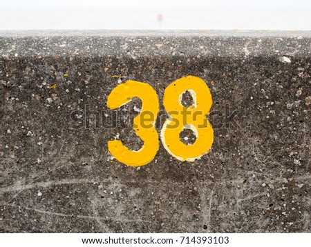 a yellow numbering with paint on sea front wall Harwich 38; England; UK