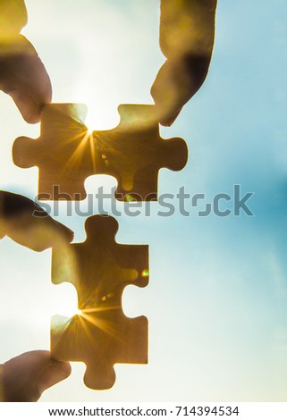 two hands trying to connect couple puzzle piece with sunset background. empty space. Jigsaw wooden puzzle against sun rays. two part of whole. symbol of association and connection. business strategy