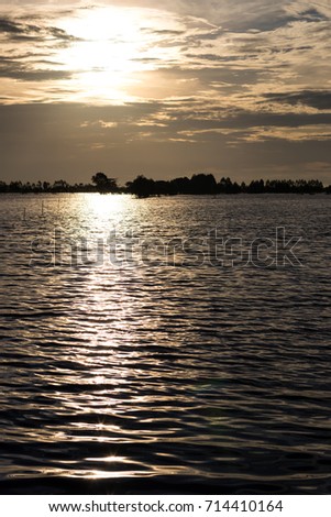 Ripple-wave scenery on a vast surface of water in rural Thai agriculture with flashing sunlight in the early morning.