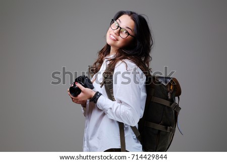 Positive female tourist with photo camera and travel backpack.