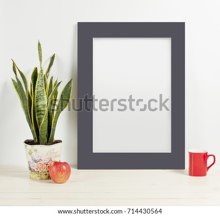 Mock up of blank photo frame with plant pot, mug and apple on wooden shelf