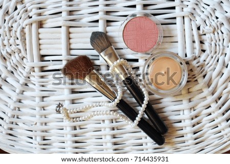 make-up brushes with black handles, contouring face, blush, pearl thread, on white wicker background, selective focus, close-up