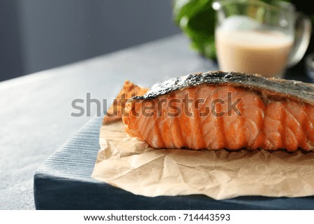 Board with slice of delicious salmon on table