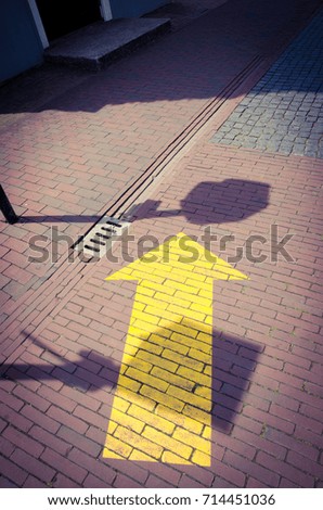 Yellow forward arrow sign on brick floor.